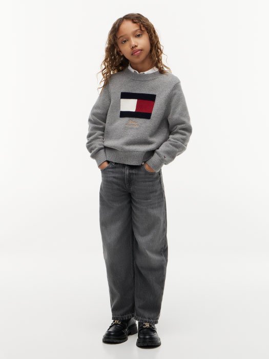 Meisje met grijze Tommy Hilfiger trui en jeans uit de najaarscollectie